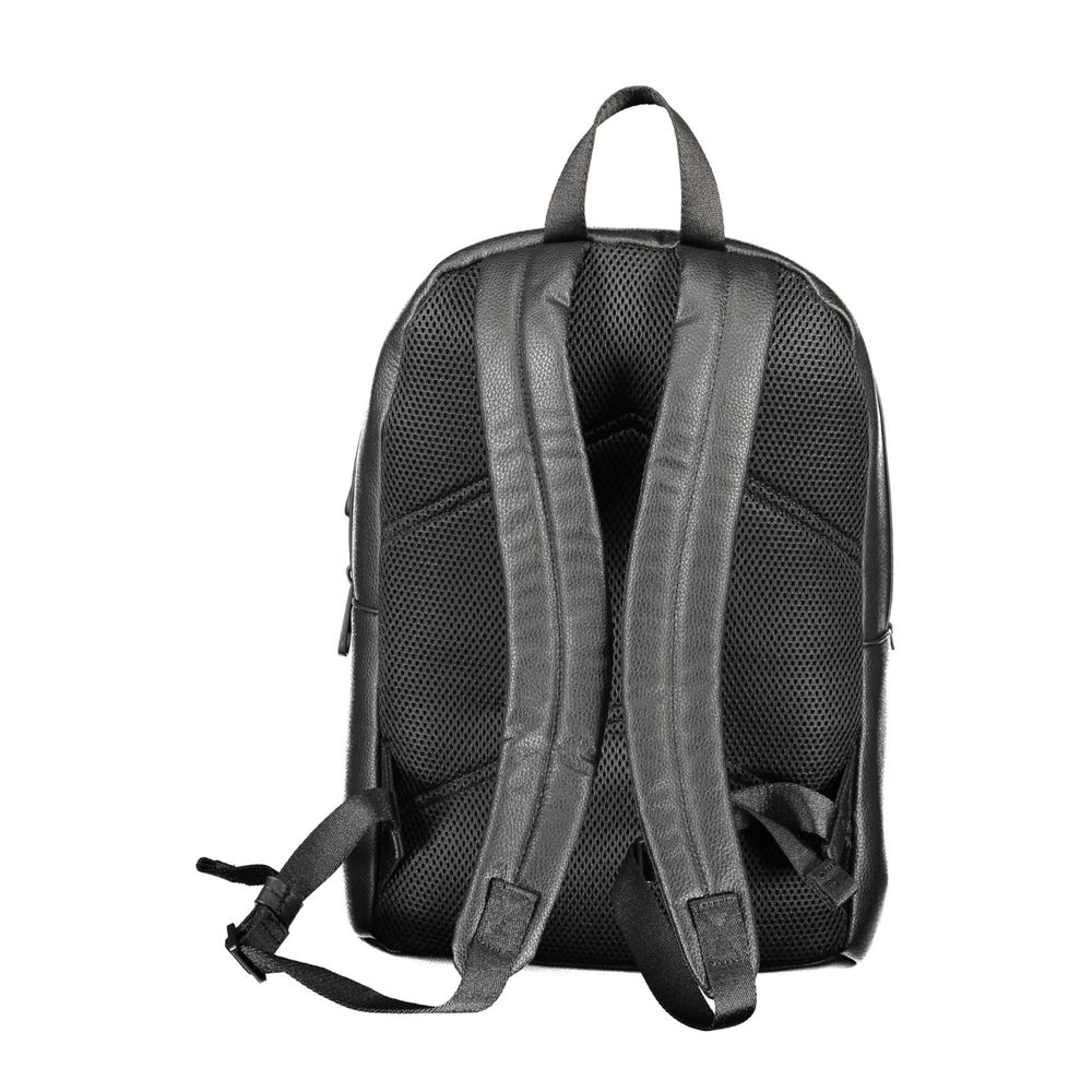 The Calvin Klein Nero Poliuretano Men Backpack is shown from the back, with two padded shoulder straps, a top handle, and a breathable textured back panel. One strap hangs loose. Made from recycled polyester.