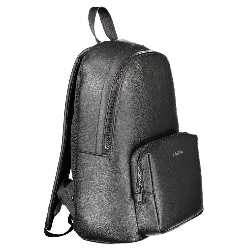 The Calvin Klein Nero Poliuretano Men Backpack is a sleek black bag with a top handle, adjustable straps, spacious main compartment with laptop sleeve, zip front pocket, and subtle logo.